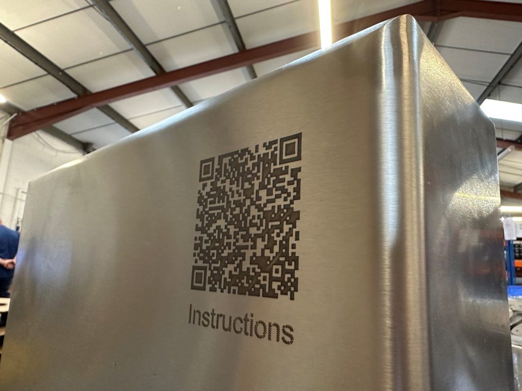 A laser-etched QR code marked onto a brushed stainless steel panel